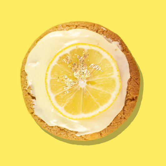 Lemon Cheesecake Maxi cookie with white chocolate base, lemon-infused cream cheese frosting, and a lemon slice on top.