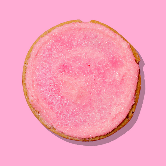 Glinda Maxi cookie with pink cake batter cream cheese frosting and sparkling pink sugar on a white chocolate base.