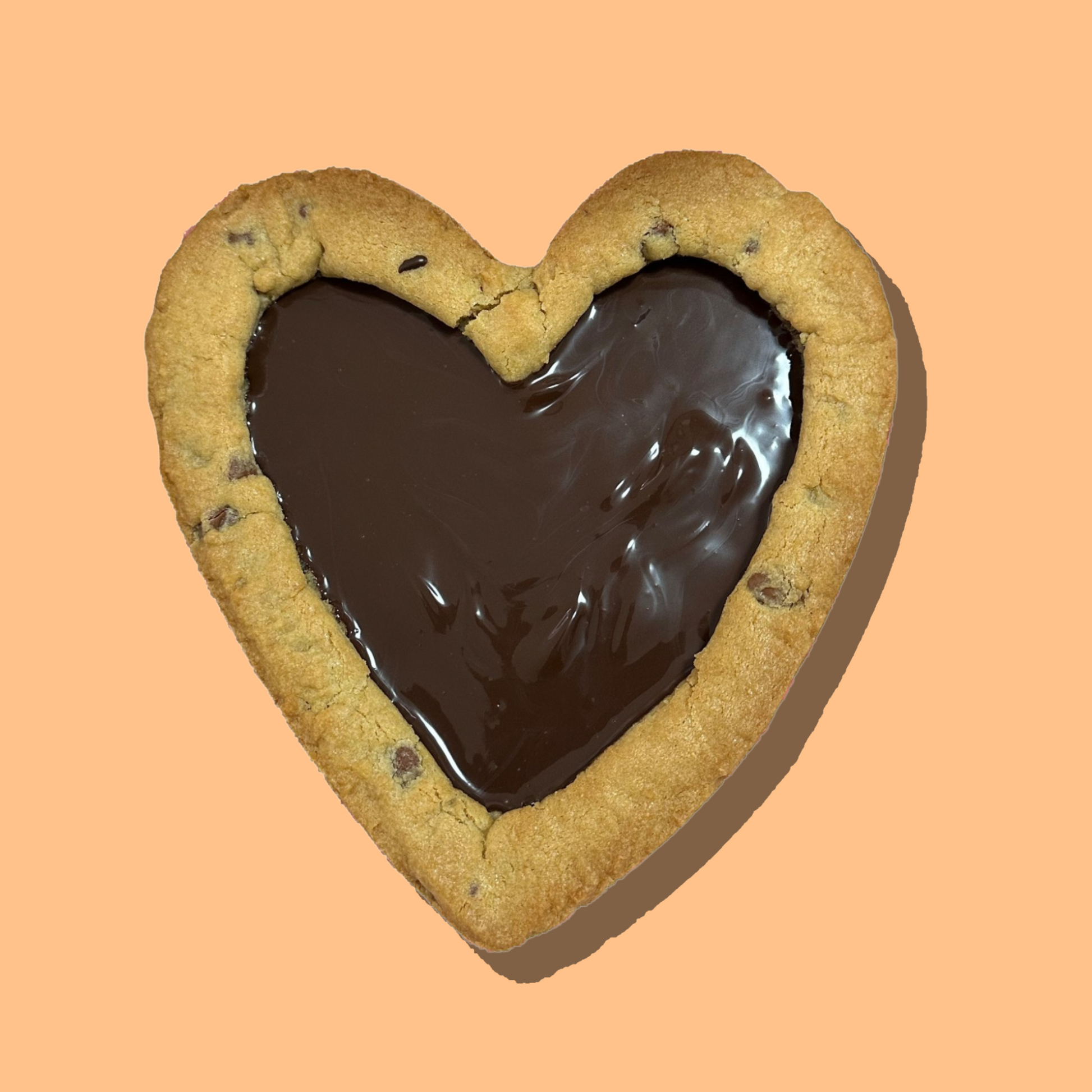 Heart-shaped cookie pie with chocolate center on peach background.