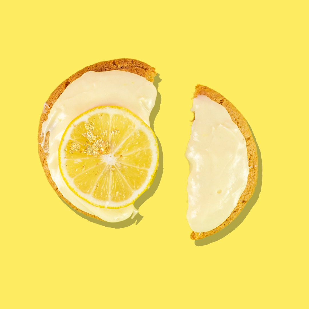 Lemon cheesecake cookie with white chocolate base, lemon frosting, and a lemon slice.