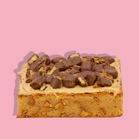 Loaded Caramilkie brownie with chocolate topping on a pink background.